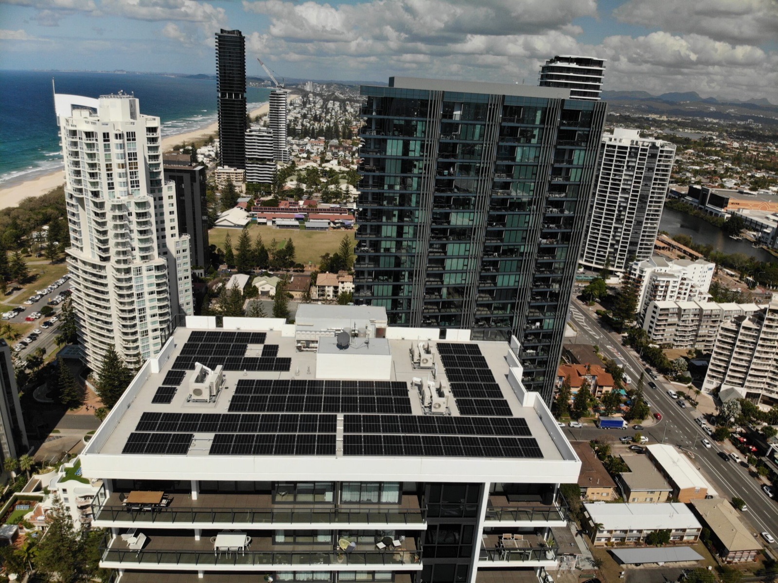Rooftop solar array installed by Thomas Electrical and Solar on a Gold Coast high-rise, with the beach and skyline behind