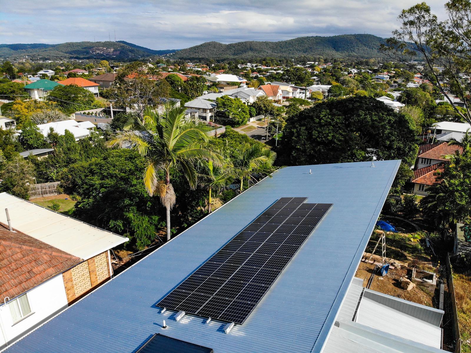 Long solar array on a pale blue metal roof with the coastline in the distance