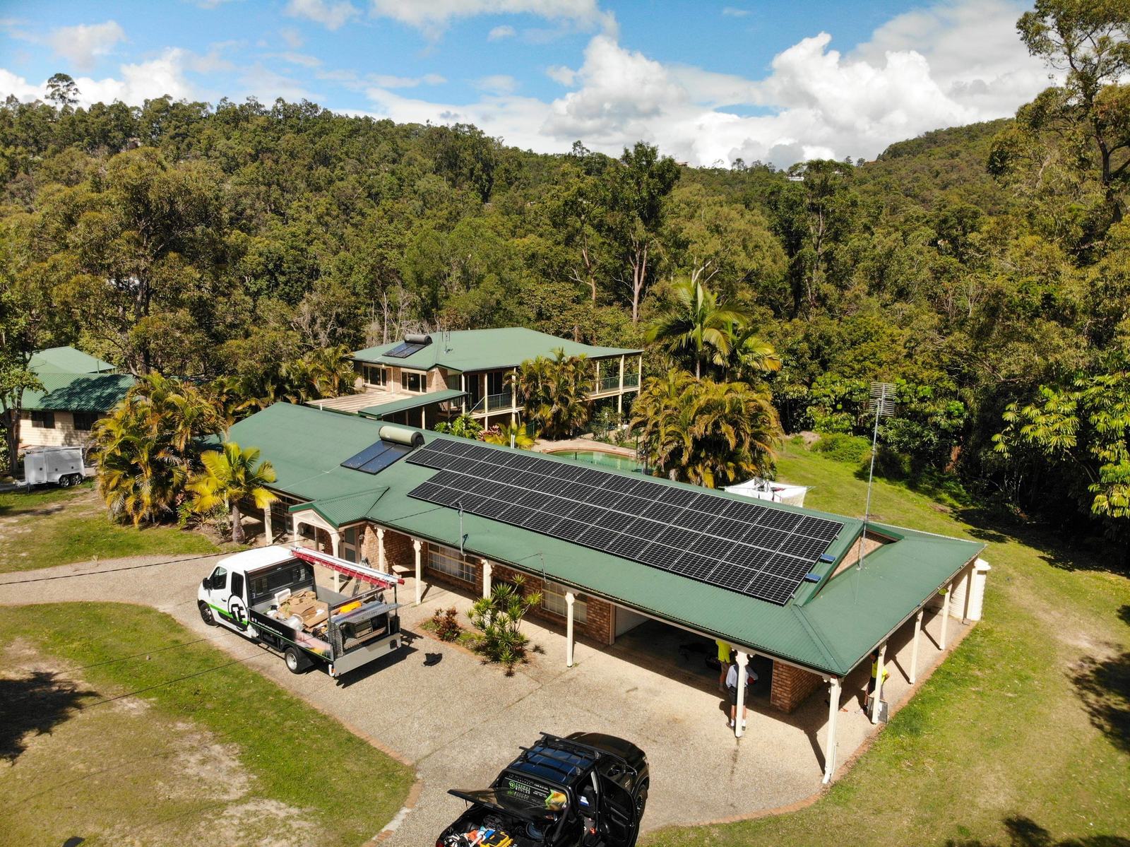 Hinterland home with a full solar array on its green roof and a Thomas Electrical work truck parked in the driveway